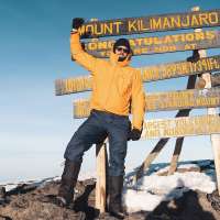 Erik Conover poses atop the summit of Mount Kilimanjaro